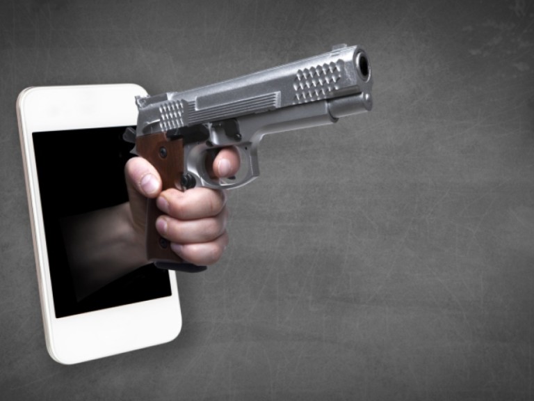 Illustratie van een hand met een pistool die uit het scherm van een smartphone steekt, tegen een grijze achtergrond.