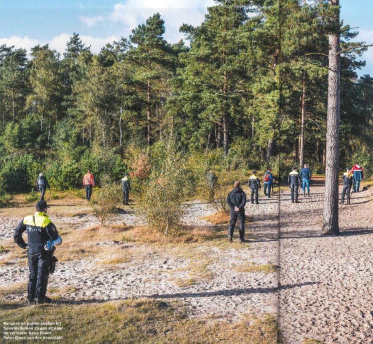 Burgers en agenten zoeken verspreid over een zandvlakte langs een bos; volgens het bijschrift zoeken ze bij de Soesterduinen zij aan zij naar de vermiste Anne Faber (foto Goos van der Veen/ANP).