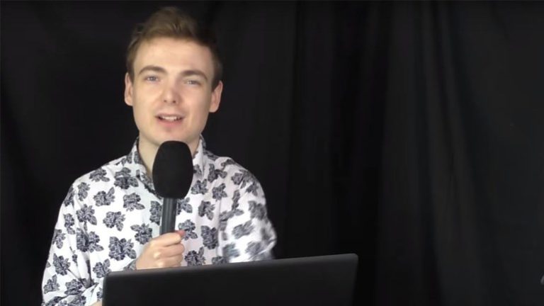 Vlogger Sven van der Meulen in een overhemd met bloemenprint, met een microfoon in de hand voor een zwart gordijn, in een beeld van zijn YouTube-kanaal Vrije Vogels.
