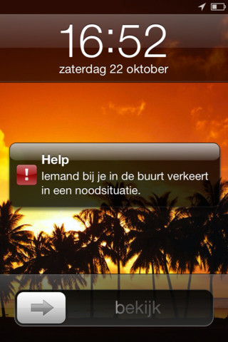 Vergrendelscherm van een iPhone met een melding van de Help-app: “Iemand bij je in de buurt verkeert in een noodsituatie.”, op een achtergrond met palmbomen bij zonsondergang.