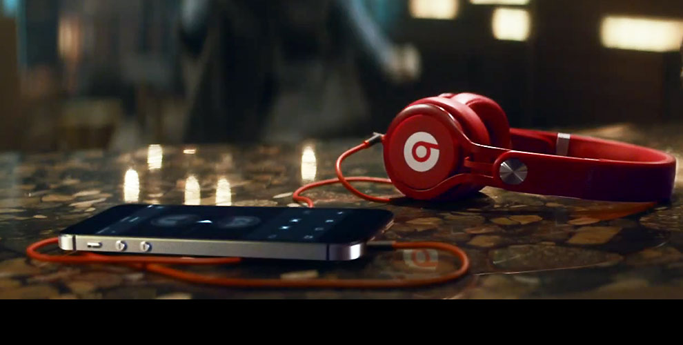 Rode koptelefoon van Beats die met een rood snoer is aangesloten op een smartphone op een glanzende stenen tafel.