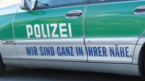 Zijkant van een groen-witte Duitse politieauto met het opschrift “Polizei” en “Wir sind ganz in Ihrer Nähe”.