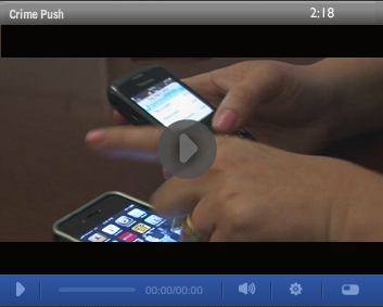 Stilstaand beeld uit een video over Crime Push van 2:18 minuten, met handen die twee smartphones bedienen en een afspeelknop in het midden.