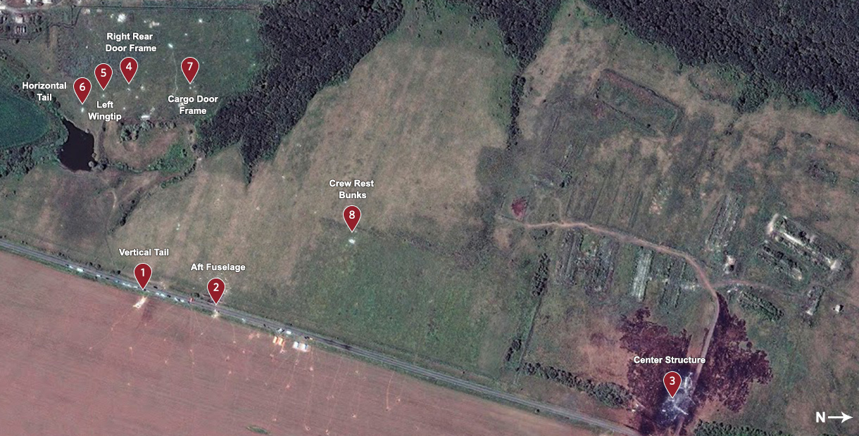 Satellietbeeld van het rampgebied met acht genummerde markeringen voor vliegtuigdelen, zoals de verticale staart, de achterromp, het middengedeelte en het kader van de vrachtdeur.