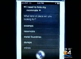 Tv-beeld van een iPhone-scherm met Siri: op de vraag “I need to hide my roommate” volgt “What kind of place are you looking for?” met de opties swamps, reservoirs, metal foundries, dumps en mines.