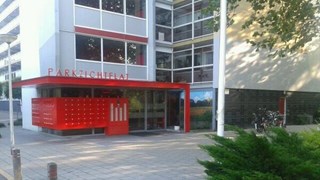 De ingang van de Parkzichtflat in Deventer met rode brievenbussen en de naam “Parkzichtflat” op de rode luifel.