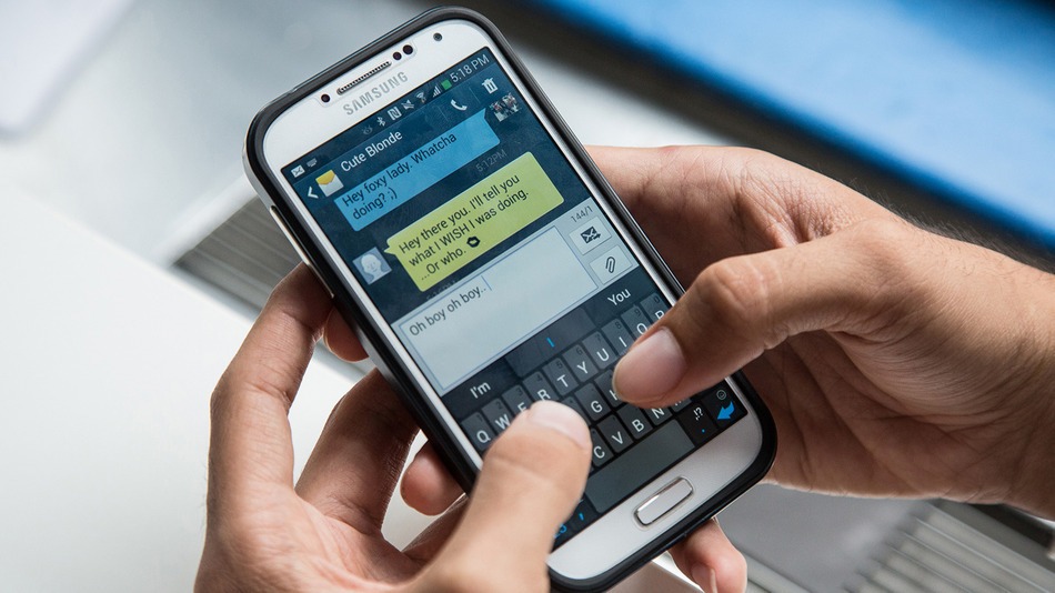 Handen typen op een smartphone een flirterig berichtje aan een contact met de naam “Cute Blonde”.