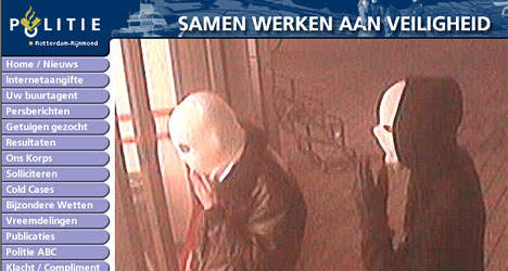 Schermafbeelding van de website van politie Rotterdam-Rijnmond met de kop “Samen werken aan veiligheid”, een menu en een camerabeeld van twee gemaskerde overvallers.