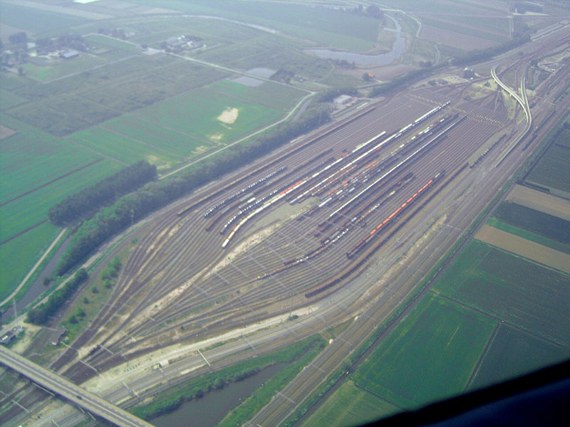Luchtfoto van rangeerterrein Kijfhoek: tientallen sporen met goederenwagons tussen groene weilanden.