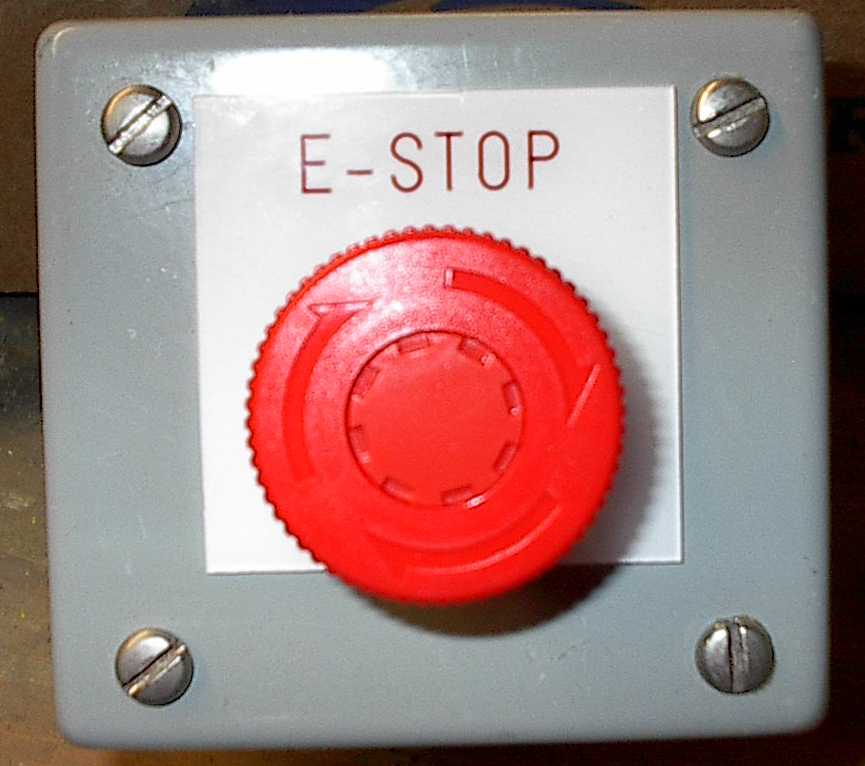 Grijs kastje met een grote rode noodstopknop en het opschrift “E-STOP”.