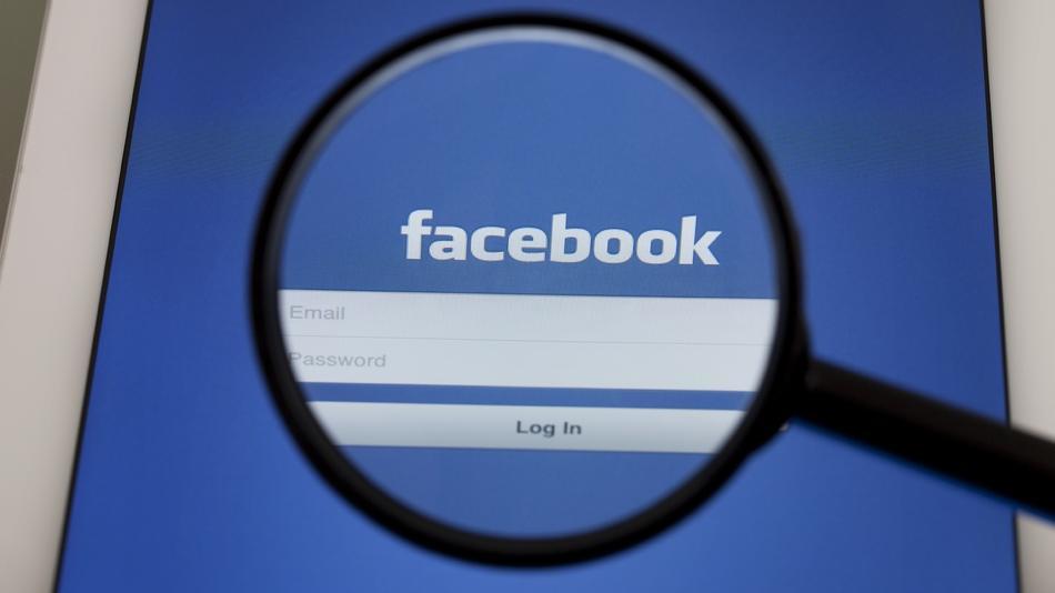 Een vergrootglas boven het inlogscherm van Facebook, met het logo en de velden voor e-mail en wachtwoord.