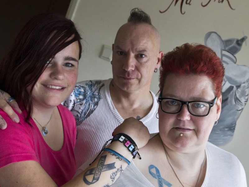Tatoeëerder Peter Maas (midden) met Mandy Claessens (links) en Annet Meulendijk (rechts), die hun verse herdenkingstatoeages voor de MH17 laten zien: een rouwlint op onderarm en schouder.