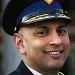 Portretfoto van Martin Sitalsing, voormalig hoofdcommissaris van de politie Twente, glimlachend in uniform met pet.