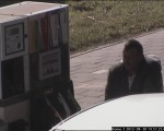 Korrelig beeld van een bewakingscamera bij een tankstation, met een man naast een pomp.
