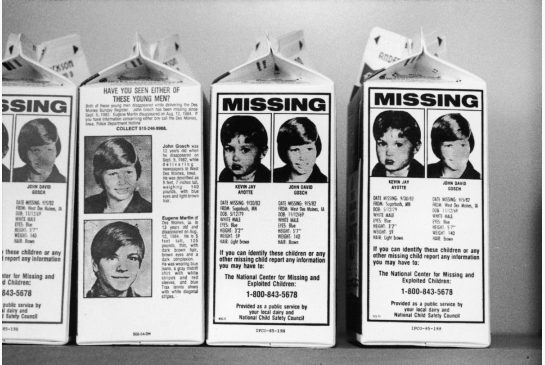 Zwart-witfoto van een rij Amerikaanse melkpakken met de kop “MISSING” en foto’s van vermiste jongens, met de oproep contact op te nemen met het National Center for Missing and Exploited Children.