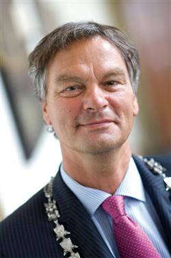 Portretfoto van burgemeester Bernt Schneiders van Haarlem in pak met roze das en ambtsketen.